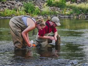Two students collecting samples in a river