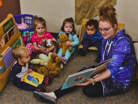 Early Childhood Development Center student staff reading to a small group of children