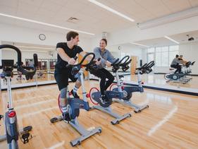 Two students sitting on spin bikes in the Wellness Center