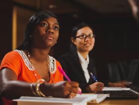 Two students taking notes in the Business Board Room