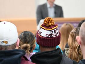 Group of students listening to a lecture with one student wearing a UMC stocking hat